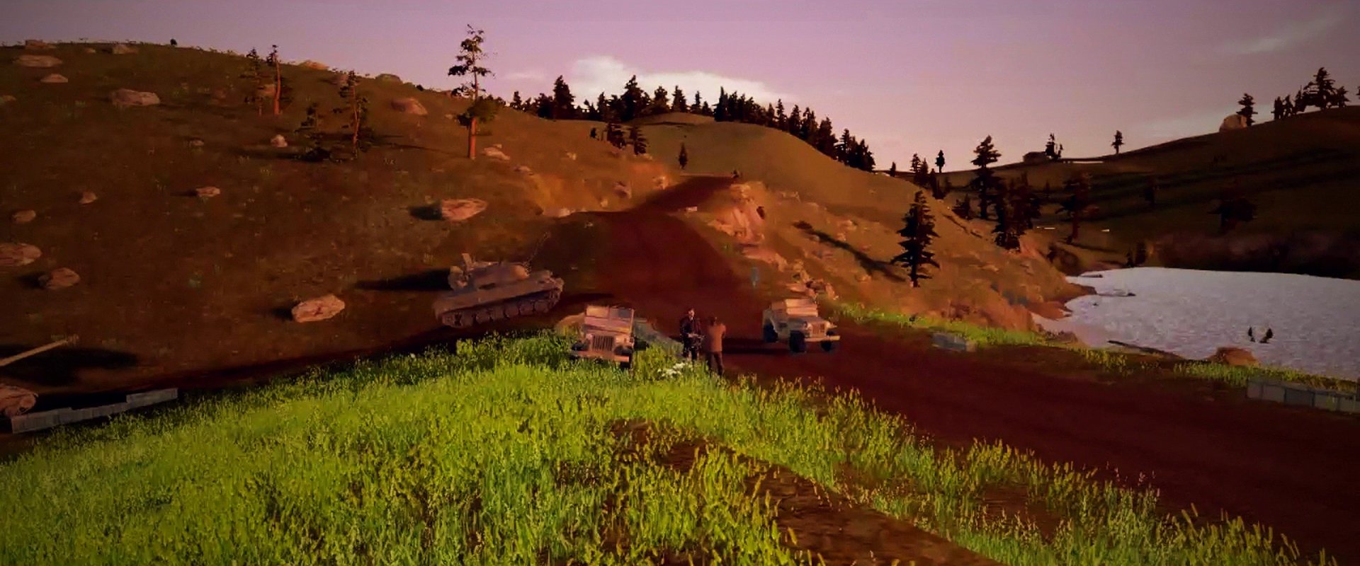 Vehicles on a track through hills at sunset